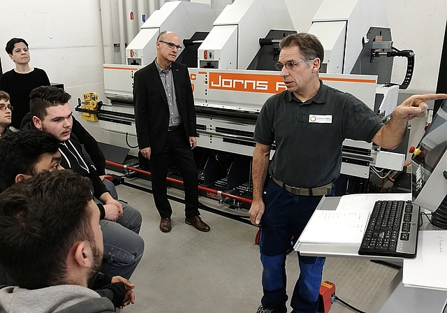 Moderne Technik: Vor der neuen Langabkantmaschine an der Berufsschule Lenzburg instruiert Fachlehrer Andreas Suter Lernende.Foto: Fritz Thut