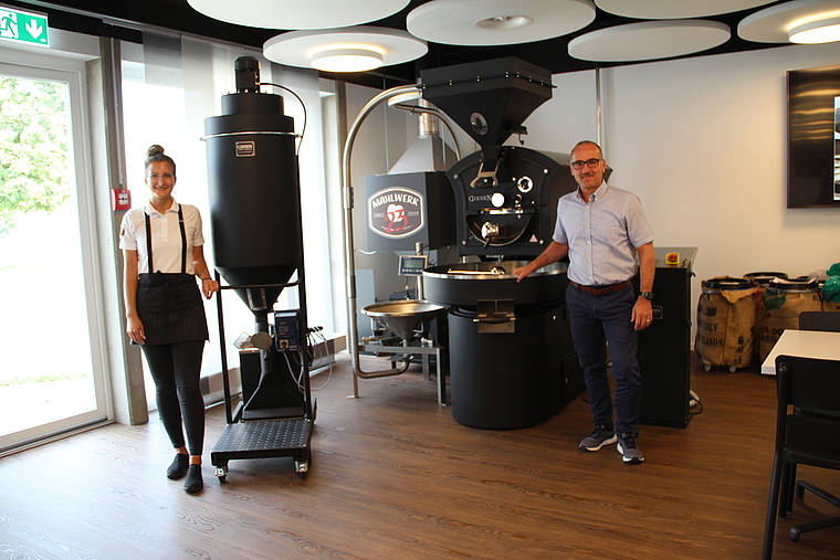 Schweizweit in einem Café einzigartig: Barista Tatjana Lukic und Geschäftsführer Martin Bhend mit der imposanten Kaffeerösterei. Foto: Carolin Frei