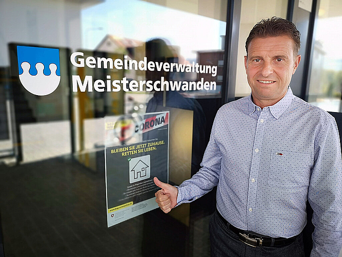 «Wir wollen Vorbild sein»: Meisterschwandens Gemeindepräsident Ueli Haller vor einem Coronaplakat beim Gemeindehaus. Foto: Fritz Thut
«Wir wollen Vorbild sein»: Meisterschwandens Gemeindepräsident Ueli Haller vor einem Coronaplakat beim Gemeindehaus. Foto: Fritz Thut