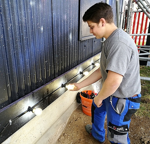 Es werde Licht: Ein Elektriker montiert und kontrolliert Glühlampen bei der Aussenbeleuchtung.
