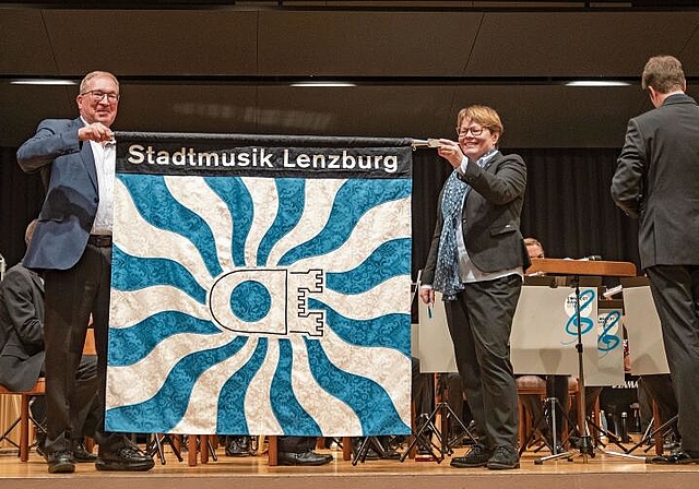 Sie soll die nächsten Jahre den Weg weisen: Die neue Fahne der Stadtmusik, entrollt von Markus Blättler und Marianne Wildi. Foto: Peter Winkelmann
