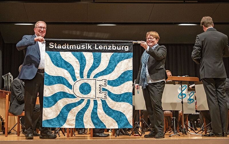 Sie soll die nächsten Jahre den Weg weisen: Die neue Fahne der Stadtmusik, entrollt von Markus Blättler und Marianne Wildi. Foto: Peter Winkelmann
