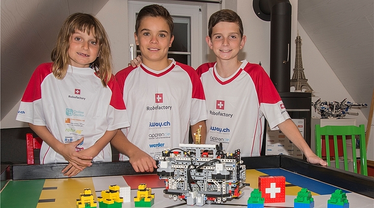 Noch todmüde, aber schon wieder am Roboter: Nina (7 Jahre), Elias (12) und Jesse (11) sind stolz auf das Erlebnis «World Robot Olympiad» in Costa Rica. Foto: Peter Winkelmann