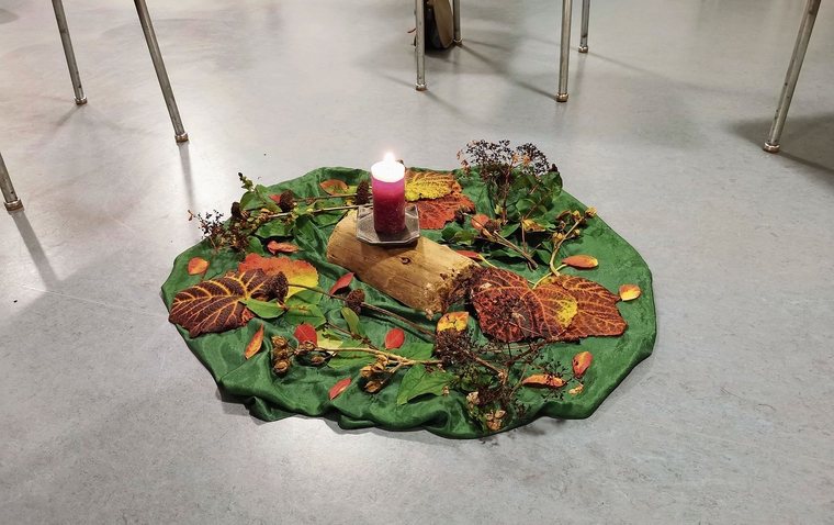 In der Mitte des Stuhlkreises eine Kerze und buntes Herbstlaub.Foto: Verena Schmidtke