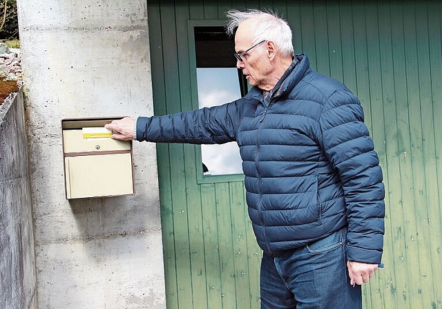 Gehört in Holderbank seit dem 8. März der Vergangenheit an: Lorenz Caroli mit dem Steckschild der Post, das in der ganzen Schweiz sukzessive durch Online-Lösungen ersetzt wird. Foto: Carolin Frei
