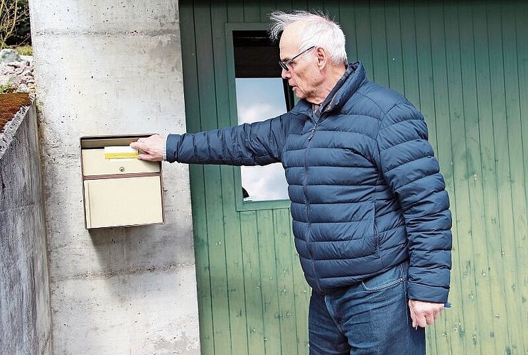 Gehört in Holderbank seit dem 8. März der Vergangenheit an: Lorenz Caroli mit dem Steckschild der Post, das in der ganzen Schweiz sukzessive durch Online-Lösungen ersetzt wird. Foto: Carolin Frei
