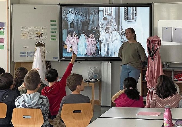 Schüler als interessierte Zuhörer: Tamara Stumpf erklärt den Hallwiler Brauch des «Wiehnechts-Chindli». Foto: Andreas Walker