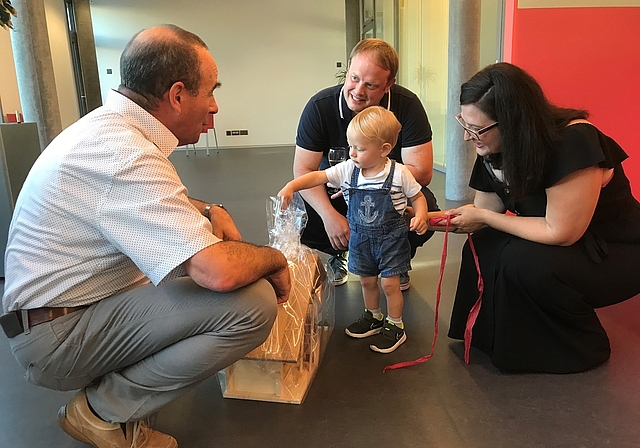 Begrüssung mit Geschenken: Gemeindeammann Otto Moser (links) und die Eltern Björn Thewes und Berkenda Frrokaj schauen Jakob beim Auspacken des Holzbauernhofes zu. Foto: Hanny Dorer