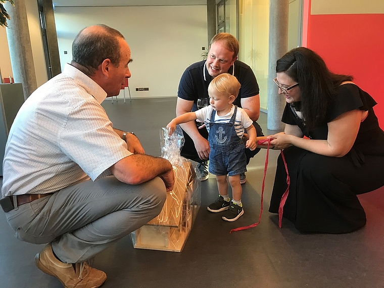 Begrüssung mit Geschenken: Gemeindeammann Otto Moser (links) und die Eltern Björn Thewes und Berkenda Frrokaj schauen Jakob beim Auspacken des Holzbauernhofes zu. Foto: Hanny Dorer