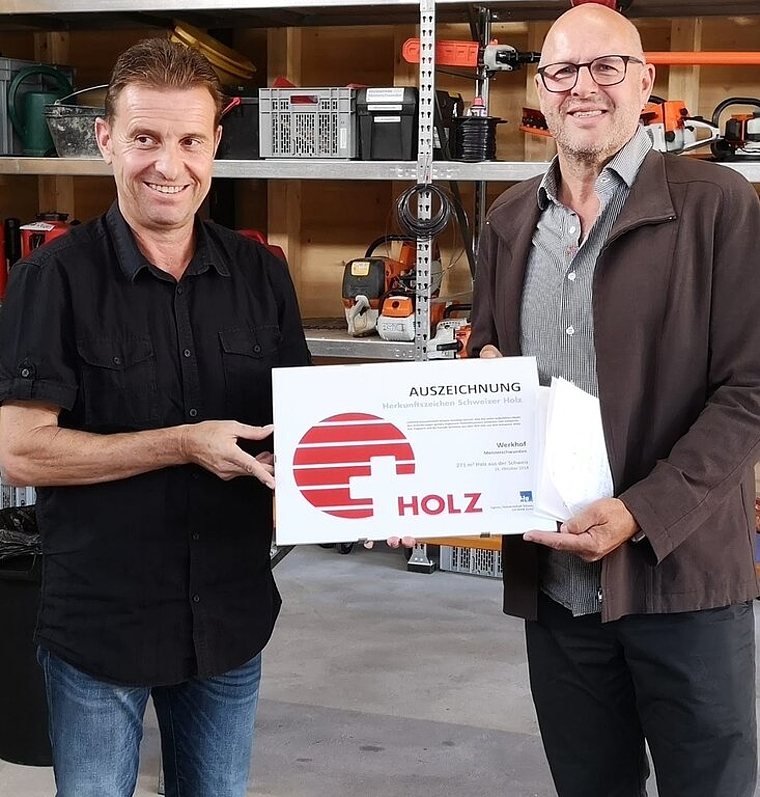 <em>Übergabe:</em> Gemeindepräsident Ueli Haller erhält von Hansbeat Reusser vom Branchenverband Lignum die Auszeichnung «Herkunftszeichen Schweizer Holz». Foto: tf