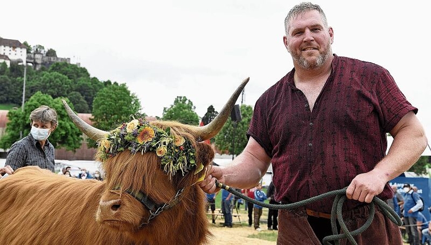 Bärbeli bleibt hier: Schwingerkönig Christian Stucki posiert mit dem Siegerpreis, dem schottischen Hochlandrind von Züchterin und Spenderin Brigitte Vogel (hinten links). Foto: Alexander Wagner
