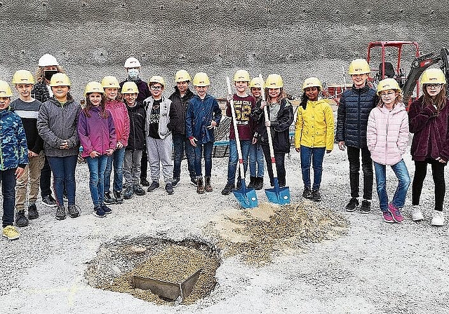 Bald ist die Zeitkapsel ganz mit Sand bedeckt: Die Viertklässler mit der Gemeinderätin Sonja Gygli und ihrer Lehrerin Karin Fosco bei der Grundsteinlegung. Foto: Carolin Frei