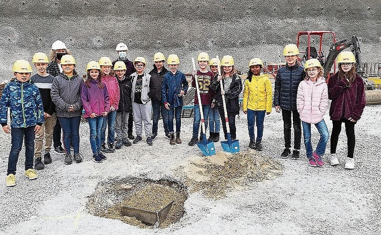 Bald ist die Zeitkapsel ganz mit Sand bedeckt: Die Viertklässler mit der Gemeinderätin Sonja Gygli und ihrer Lehrerin Karin Fosco bei der Grundsteinlegung. Foto: Carolin Frei