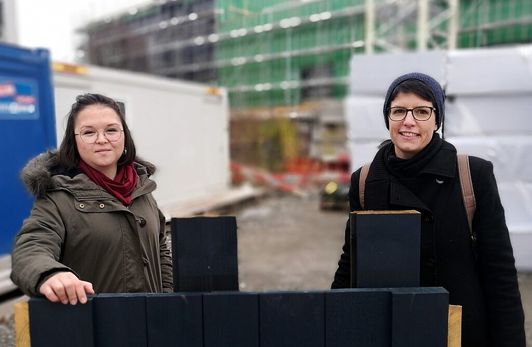 Blick hinter die Kulissen: Emel Ilter und Andrea Grossenbacher vom Stapferhaus hinter einem blauen Fassadenmuster und vor dem Rohbau des neuen Sitzes am Lenzburger Bahnhof, der am Samstag besichtigt werden kann.Foto: Fritz Thut