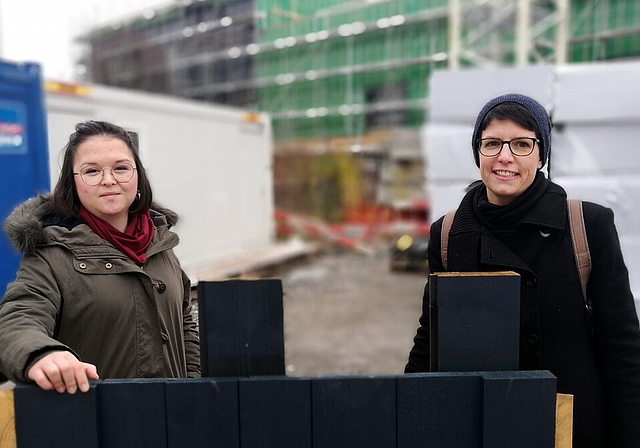 Blick hinter die Kulissen: Emel Ilter und Andrea Grossenbacher vom Stapferhaus hinter einem blauen Fassadenmuster und vor dem Rohbau des neuen Sitzes am Lenzburger Bahnhof, der am Samstag besichtigt werden kann.Foto: Fritz Thut