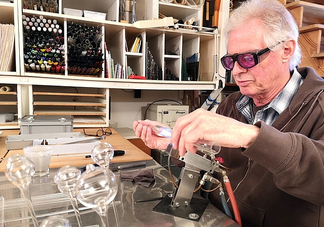 <em>Mit Schutzbrille ausgerüstet am Werken:</em> Glaskünstler Hans-Peter Eichenberger in seinem Atelier am Keltenweg. Fotos: Fritz Thut