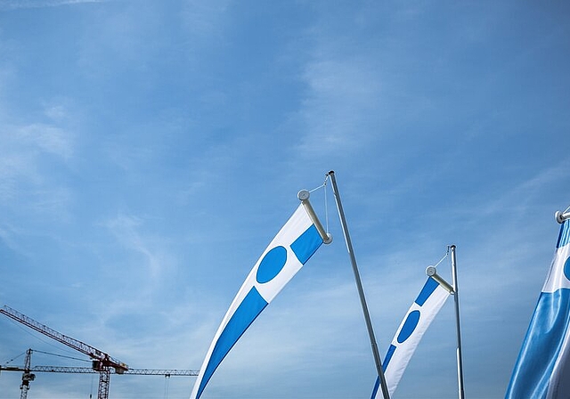 <em>Bauliche Entwicklung in Leitbild und Legislaturzielen nicht erwähnt:</em> Krane und Lenzburger Fahnen unter blauem Himmel. Foto: Chris Iseli