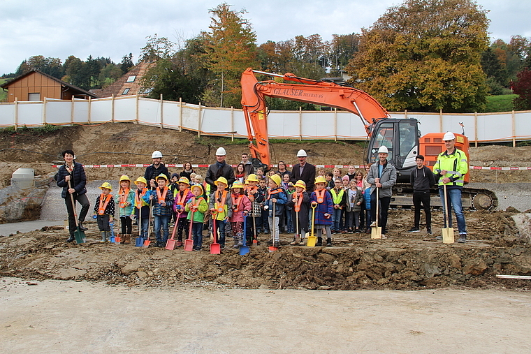 Die Freude über den lang ersehnten Baustart ist unübersehbar: Endlich konnte der Spatenstich mit Kindergärtlern, Schülern, Lehrpersonen, Architekten, Bauleitung und Gemeindeammann Max Härri (Mitte) vollzogen werden. Foto: Carolin Frei