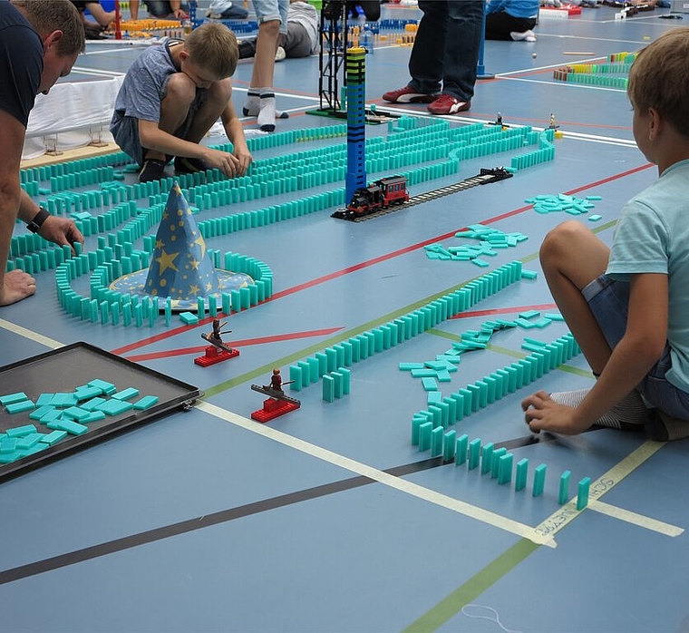 <em>Konzentriert bei der Sache: </em>Jung und Alt beim Dominoaufbau. Foto: zvg