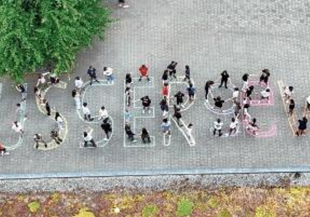 Zwischen Mehrzweckhalle und Haus 4: Schüler bilden den Schriftzug «AllesAusserGewöhnlich», das Motto des Seenger Jugendfestes 2024.Drohnenfoto: Schule Seengen