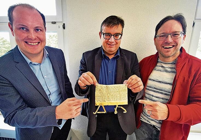 Das entscheidende Dokument: Die Erstnennungsurkunde von Dorf und Kirche Leutwil im Staatsarchiv Solothurn mit Gemeindeammann Lukas Spirgi, Staatsarchiv-Mitarbeiter Silvan Freddi und Pfarrer Michael Freiburghaus. Foto: Fritz Thut