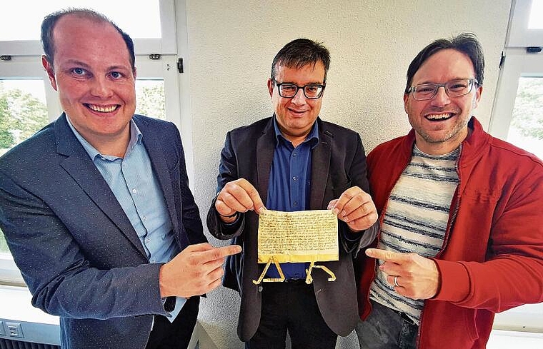 Das entscheidende Dokument: Die Erstnennungsurkunde von Dorf und Kirche Leutwil im Staatsarchiv Solothurn mit Gemeindeammann Lukas Spirgi, Staatsarchiv-Mitarbeiter Silvan Freddi und Pfarrer Michael Freiburghaus. Foto: Fritz Thut