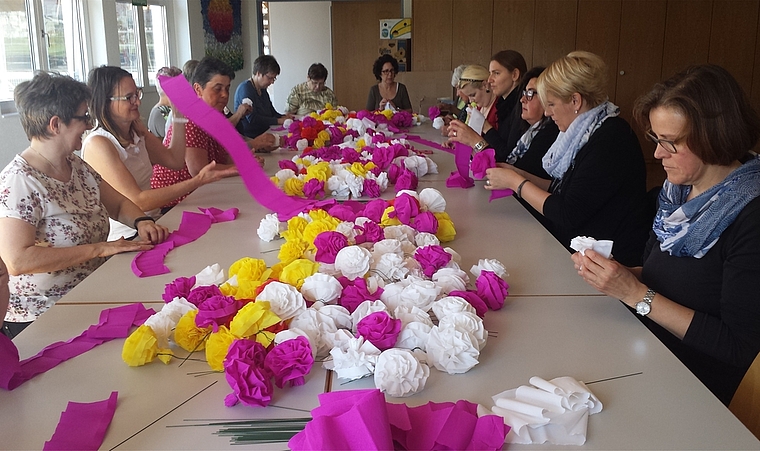 Vorbereitungen laufen auf Hochtouren: Frauen fertigen Krepprosen für das Dintiker Jugendfest. Foto: Elisabeth Hagmann