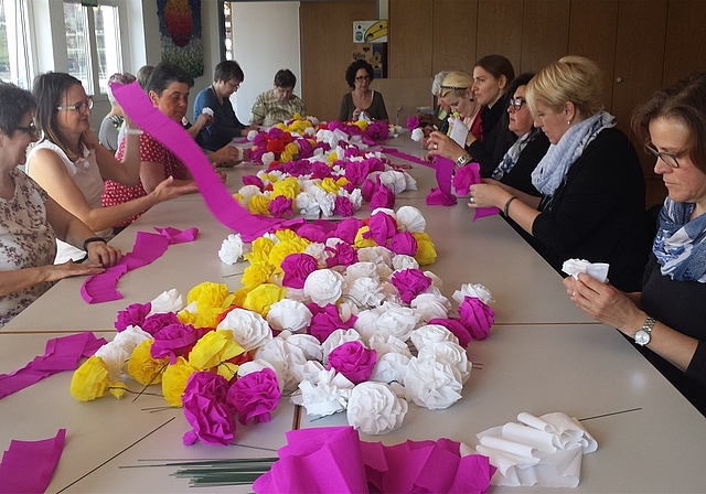 Vorbereitungen laufen auf Hochtouren: Frauen fertigen Krepprosen für das Dintiker Jugendfest. Foto: Elisabeth Hagmann