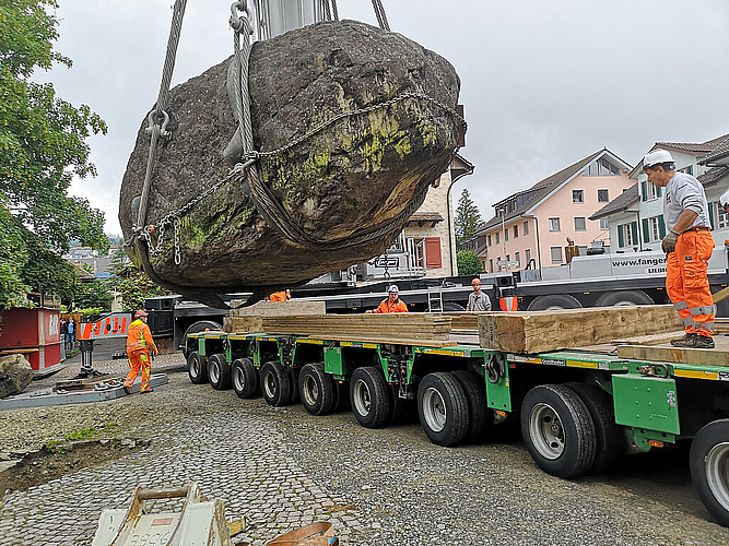 Auf zur nächsten Reise: Mit einem grossen Pneukran wird der Findling beim Burgturm auf den Spezialtransporter gehievt. Foto: Fritz Thut
