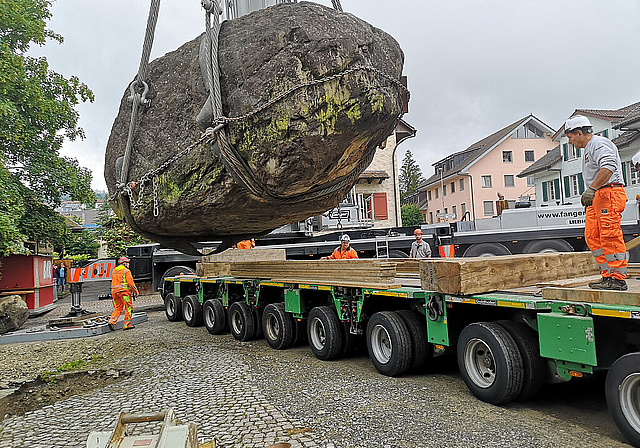 Auf zur nächsten Reise: Mit einem grossen Pneukran wird der Findling beim Burgturm auf den Spezialtransporter gehievt. Foto: Fritz Thut
