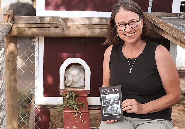 Mirjam Wicki mit ihrem neuen Jugendbuch «Hera voll viral» – und einem passenden tierischen Begleiter im Hintergrund.Foto: Romi Schmid