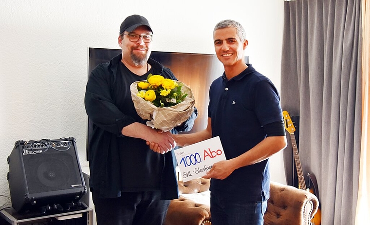 <em>Der 1000. Glasfaserkunde:</em> Marco Ringgenberg freut sich über das Geschenk, überreicht von Gian von Planta, Leiter Anlagen und Netze der SWL Energie AG. Foto: zvg
