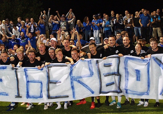 <em>Das sind die «Aufsteigerboys»:</em> Nach dem Schlusspfiff feiern die Sarmenstorfer Spieler zusammen mit ihren Fans, die das spezielle Transparent entrollt haben. Foto: Ruedi Burkart