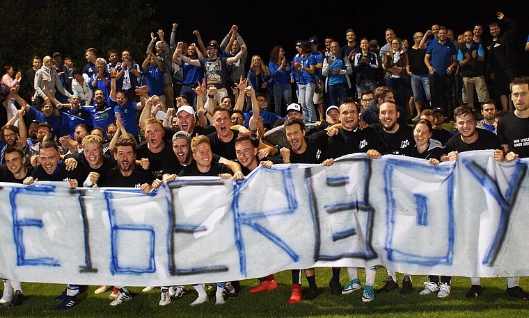 <em>Das sind die «Aufsteigerboys»:</em> Nach dem Schlusspfiff feiern die Sarmenstorfer Spieler zusammen mit ihren Fans, die das spezielle Transparent entrollt haben. Foto: Ruedi Burkart