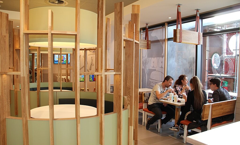 Holzlamellen, Holzsitzlehnen und Holzdeko: Der neue McDonald’s setzt bewusst auf ein warmes, einladendes Ambiente.