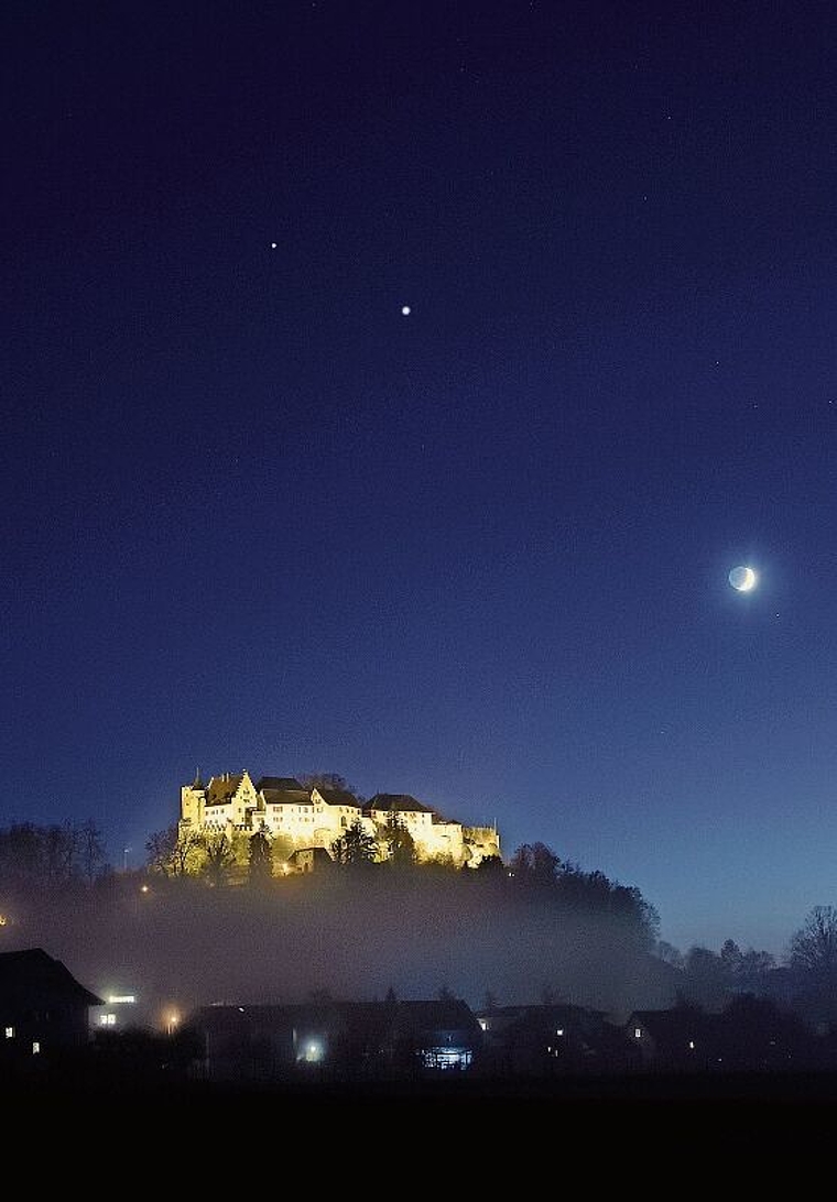 Eine stete Annäherung: Schloss Lenzburg mit Saturn (oben), Jupiter (Mitte) und Mond (rechts) am Abendhimmel, aufgenommen am 18. November. Die Planeten nähern sich immer mehr an und «verschmelzen» am 21. Dezember scheinbar zu einem Objekt. Foto: A