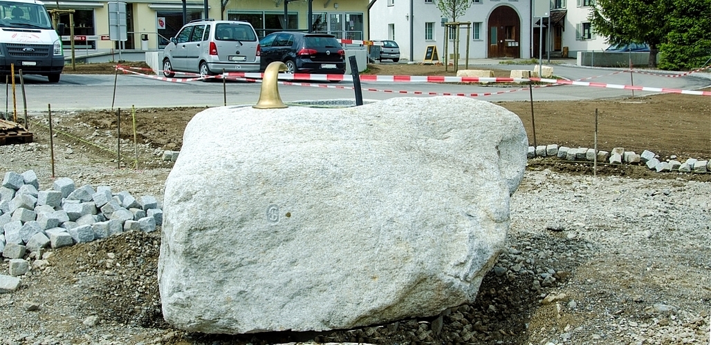 Noch ist der Dorfplatz kahl: Später wird der Brunnen von vier Sitzbänken und sechs Bäumen umgeben sein. Noch ist der Dorfplatz kahl: Später wird der Brunnen von vier Sitzbänken und sechs Bäumen umgeben sein.