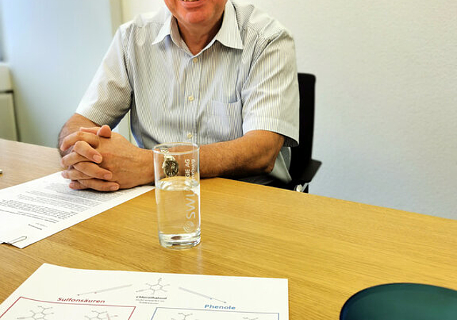 Informierte über Chlorothalonil: Markus Blättler, Geschäftsführer der SWL Wasser AG, mit einem Glas Lenzburger Wasser, einem Blatt mit Chemie-Formeln und Erdbeeren. Foto: Fritz Thut