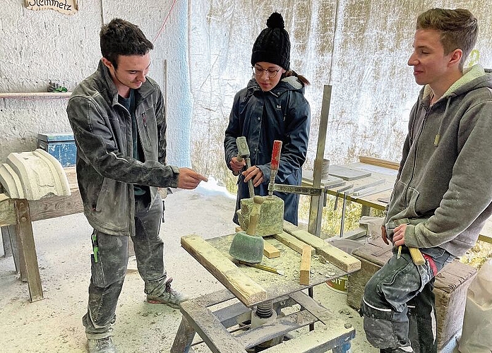 Im Atelier des Steinbruchs Hendschiken: Janik Frischknecht (2. Lehrjahr) gibt Jenna Hayoz Tipps, kritisch beobachtet von Liam Rothenbühler (4. Lehrjahr). Foto: Hanny Dorer
