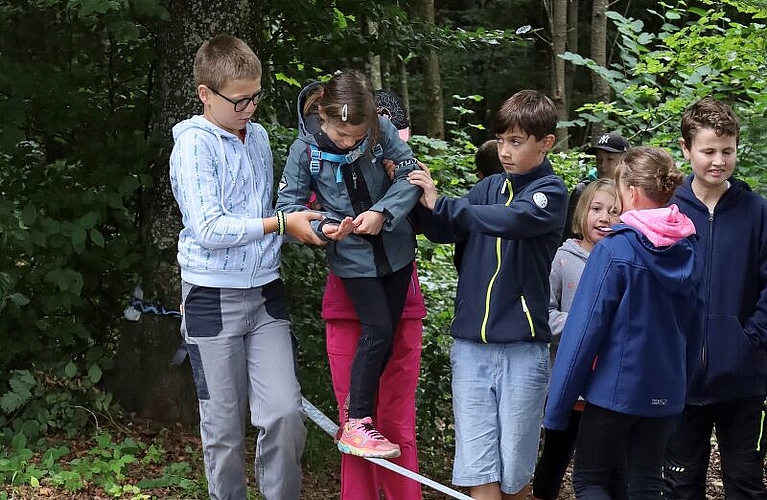 Nur im Team möglich: Kinder transportieren einen Löffel voller Wasser über die Slackline. Foto:  Tanja Isler