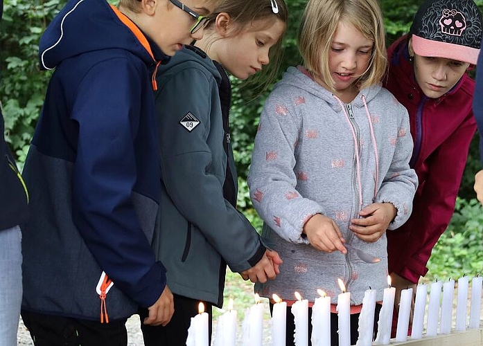 Symbolisches Bekämpfen eines Waldbrandes: Löffel für Löffel löschen die Kinder die brennenden Kerzen. Foto: Tanja Isler
