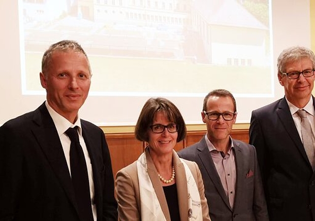 <em>Sie stehen hinter der Sanierung der Bleicherain-Schulanlage und vor einer Foto des Schulhauses:</em> Fabian von Gunten (Bauleiter), Benedikt Graf (Architekt), Monica Morgenthaler (Vertreterin BKS), Reto Kunz (Schulleiter), Daniel Mosimann (Stadta