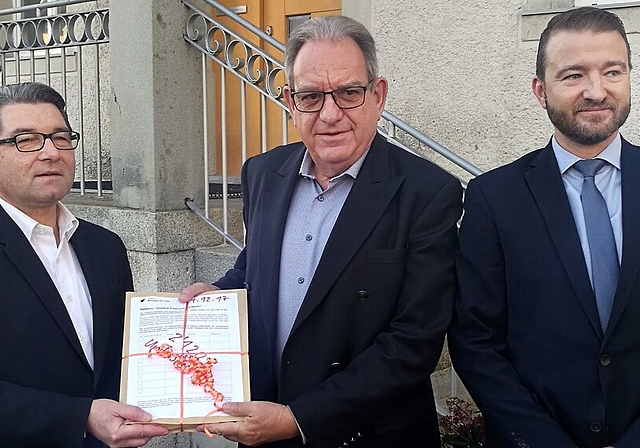 2120 Unterschriften für Erhalt der Poststelle: Vincenzo Pierdomenico, Leiter Region Aargau von der Post, übernimmt von Gemeindeammann Peter Lenzin die Petition, rechts André Aregger, Post-Netzentwicklung. Foto: Fritz Thut