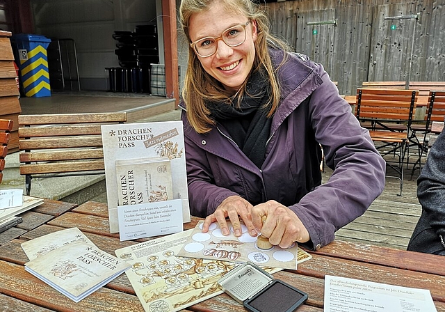 <em>Neue Attraktionen im zweiten Jahr:</em> Drachental-Projektleiterin Marianne Naunheim stempelt einen Drachen-Forscher-Pass. Foto: Fritz Thut