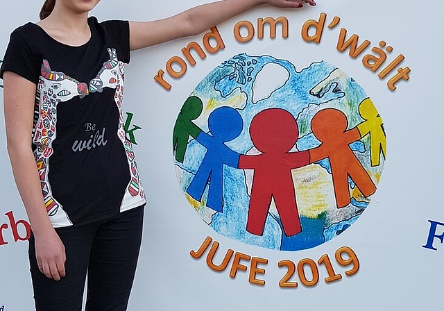 <em>Zurecht stolz auf das eigene Werk:</em> Klara Wehrle posiert vor dem von ihr entworfenen Jugendfest-Logo. Foto: zvg