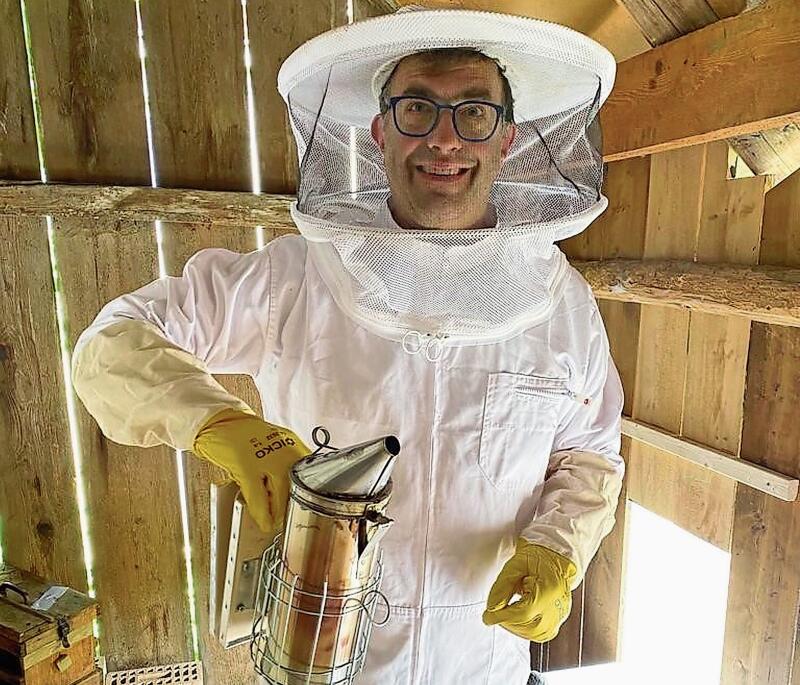 Zur Beruhigung der Bienen: Imker Tobias Keller in Schutzkleidung und mit dem Smoker in Händen in seinem Bienenstand.Foto: zvg