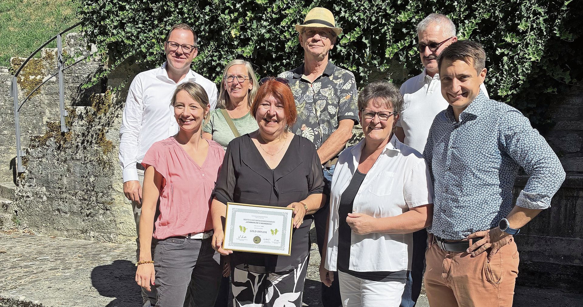Corin Ballhaus nimmt das Golddiplom entgegen. Mit auf dem Bild Stadträtin Christina Roth, Milly Stöckli, Präsidentin des Ortsbürgerverbands Aargau, Stadtpräsident Andreas Schmid (vorn, von links). Grossrat Rolf Wehrli, OK-Präsident der Ortsbürgerweinprämierung, Marianne Plüss-Marmy, Werner Volkmar und Roger Strozzega, alle vom Vorstand der Ortsbürger-Rebbauern-Vereinigung (hinten, von links).Foto: zvg