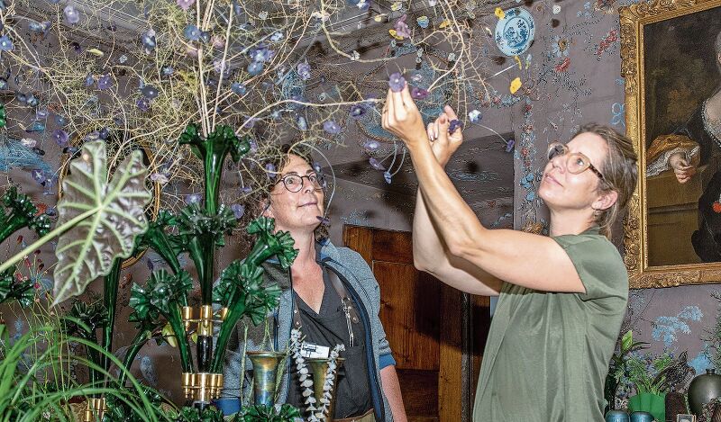 Filigrane Kunst an der Decke: Schlossfloristin Manuela Fischer (links) ist begeistert ob der Ideenvielfalt von Meisterfloristin Evelyn Krebs mit der floralen Interpretation der damaligen Geschehnisse in der Salis-Stube. Foto: Peter Winkelmann
