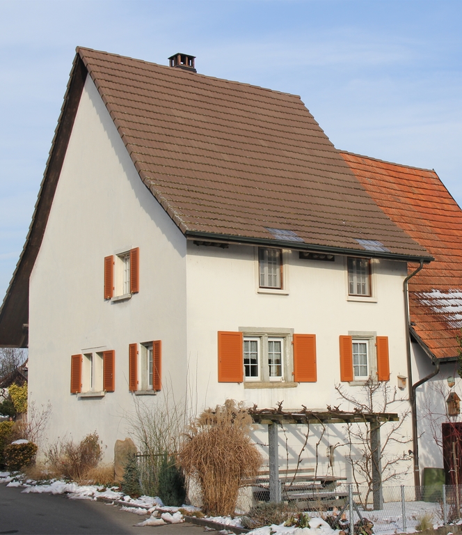 Kleinformatiges spätgotisches Bauernhaus: Gebaut 1670, zusammengesetzt aus einem schmalen, steilgieblig aufragenden gemauerten Wohnteil und einem in der Höhe abgestuften Scheunentrakt aus Holz und Stein. Der wichtige Zeuge des spätgotischen Bauens auf dem Land weist viel wertvolle originale Substanz auf.
