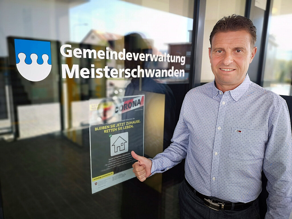 «Wir wollen Vorbild sein»: Meisterschwandens Gemeindepräsident Ueli Haller vor einem Coronaplakat beim Gemeindehaus. Foto: Fritz Thut
«Wir wollen Vorbild sein»: Meisterschwandens Gemeindepräsident Ueli Haller vor einem Coronaplakat beim Gemeindehaus. Foto: Fritz Thut